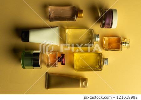 Flat lay of beauty products bottles, tub and tube with copy space on yellow background 121019992