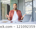 Portrait of upset and disappointed businessman, man looking displeasedly at camera while sitting inside office with laptop at workplace. 121092359