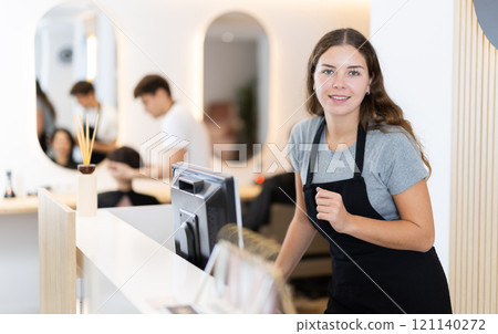 Female employee of barbershop stands near reception desk of salon, waits for visitors 121140272