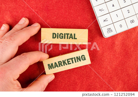 Explore effective strategies for digital marketing with wooden blocks on a red surface next to a calculator 121252094