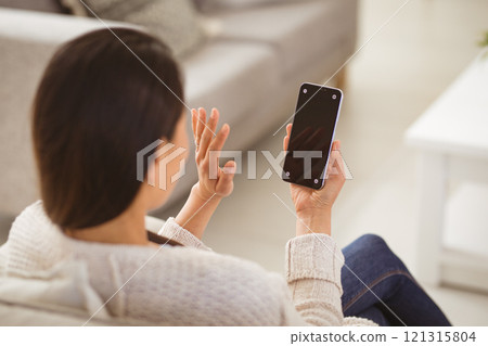 Back view of asian woman having video call on smartphone with copy space on screen 121315804