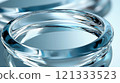 Transparent glass rings on reflective blue surface 121333523