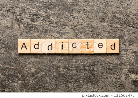 Addicted word written on wood block. Addicted text on cement table for your desing, Top view concept 121562473