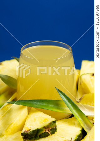 Pineapple juice in a glass among fresh pineapple fruit close-up. 121697969