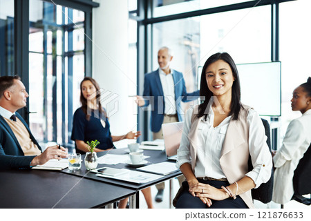 Businesswoman sitting in a modern boardroom presentation with diverse colleagues. Businesspeople brainstorming in a conference room. Happy, smiling and professional female working with her team. 121876633