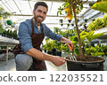 Young bearded man working with plants in a greenhouse 122035521