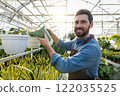 Greenhouse workers watering flowers in a glasshouse 122035525