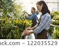 Greenhouse workers watering flowers in a glasshouse 122035529