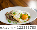 Fried eggs with boiled buckwheat and onions on a wooden table 122358783