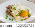 Fried eggs with boiled buckwheat and onions on a wooden table 122358784