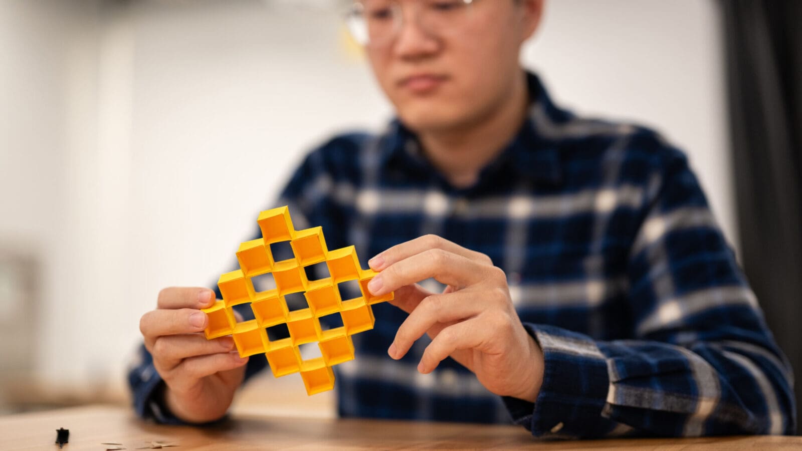 A man in a blue shirt displays a yellow, honey comb box made of cardboard