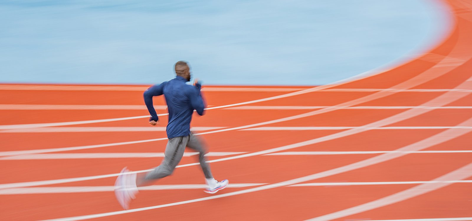 Young African American man running at tartan.