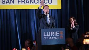 El candidato a la alcaldía Daniel Lurie, en el centro, saluda durante su fiesta de la noche electoral en San Francisco.