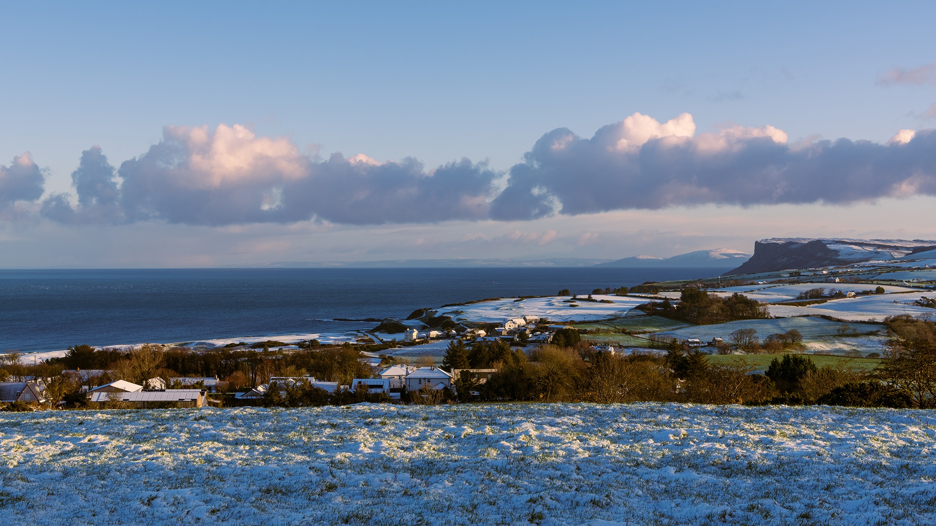 fields of snow in Ballycastle with the ocean and Fairhead in the distance