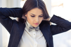 Person in a suit jacket, tying on a bow tie