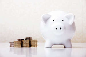 A white piggy bank next to a stack of coins