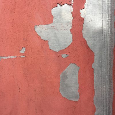 Red paint that is dirty and chipping over metal surface