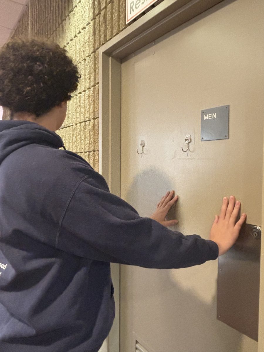 A student attempts to use the men’s restroom during class change. (Photo courtesy of Ella Colburn and Madi Hoyer.)