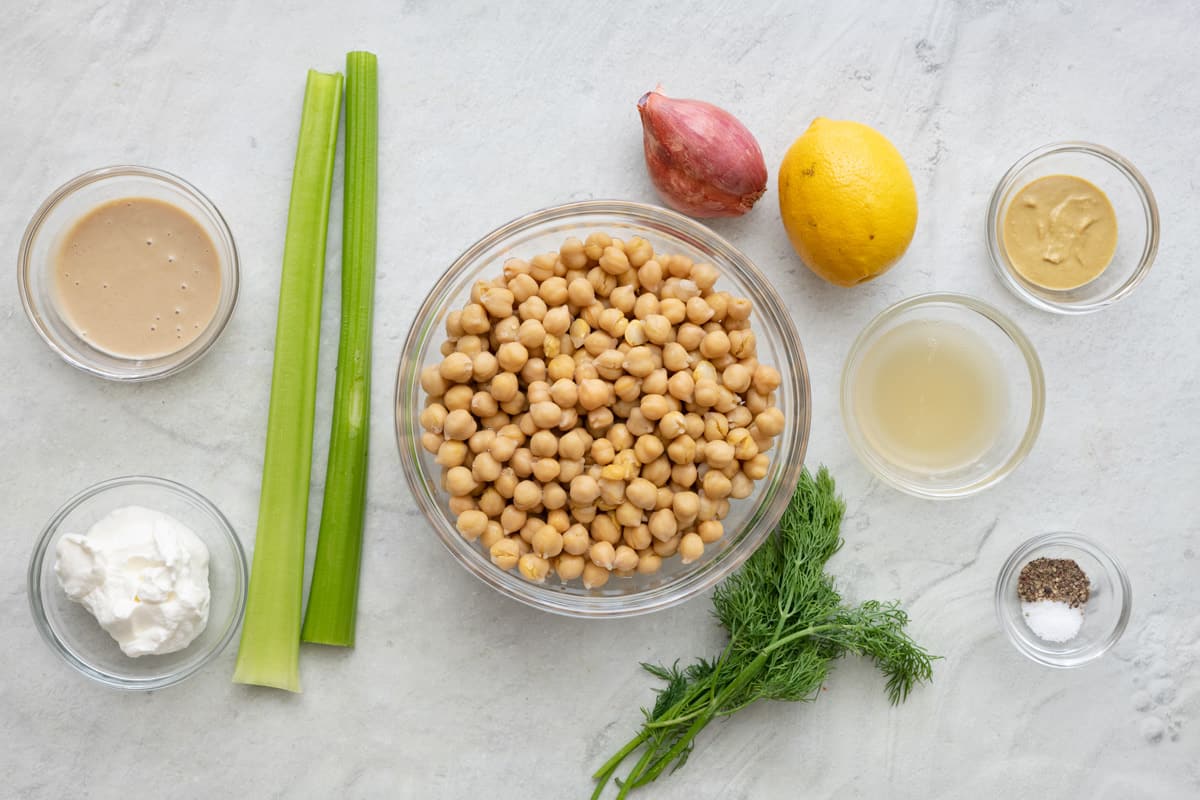 Ingredients for recipe: tahini, Greek yogurt, 2 celery stalks, chickpeas, whole shallot, whole lemon, reserved chickpea liquid, Dijon mustard, fresh dill, salt and pepper.