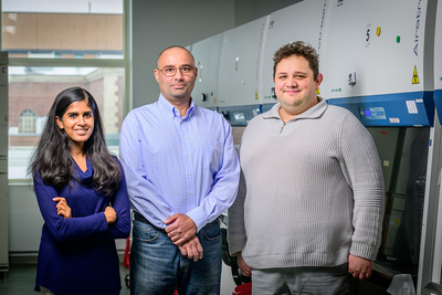 Three people stand in a lab.