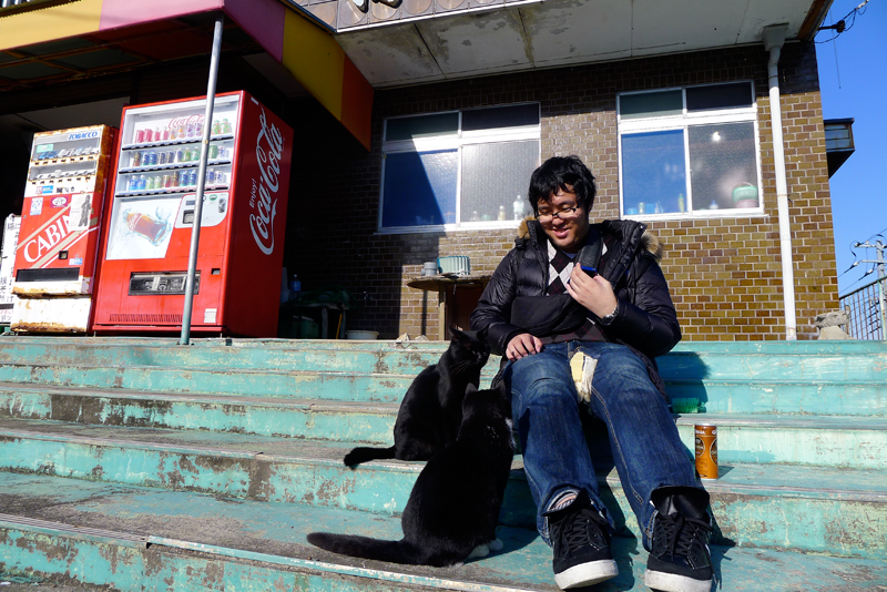 japanese man with two black cats at storefront