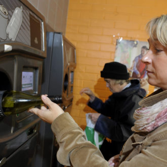 A woman places a bottle into a bottle-return machine.