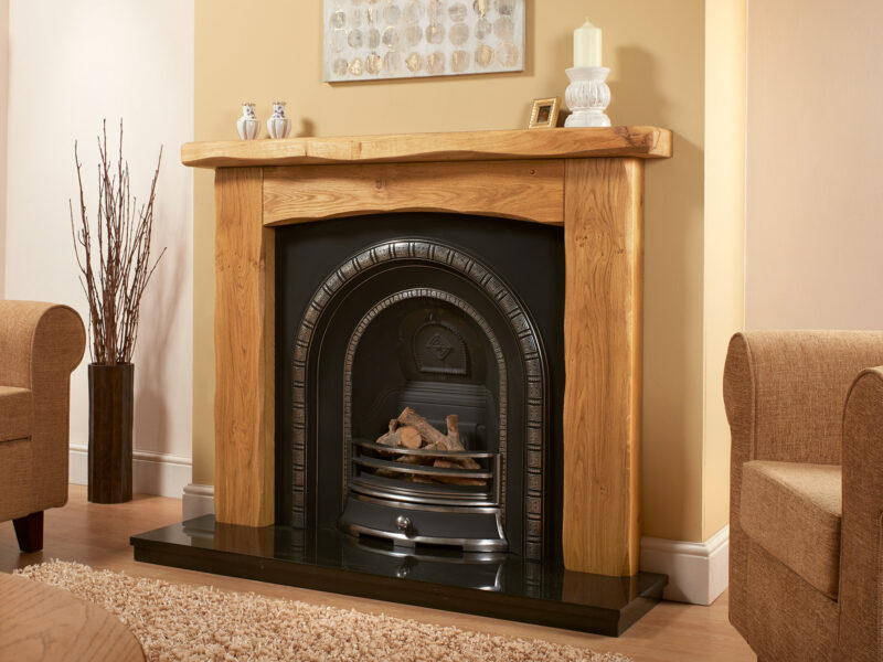 Rustic oak fireplace in light oiled oak on a yellow wall with a highlighted cast iron and granite hearth.