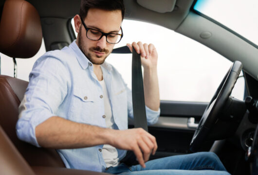 Man buckling into a rental car after paying the deposit