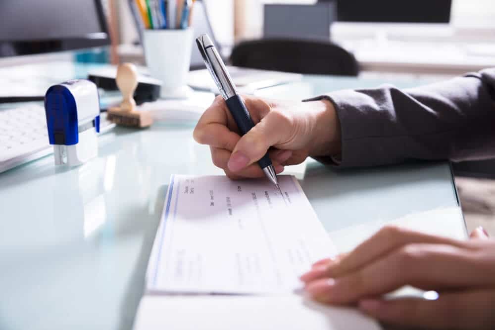 person filling out a check for cashing at a bank