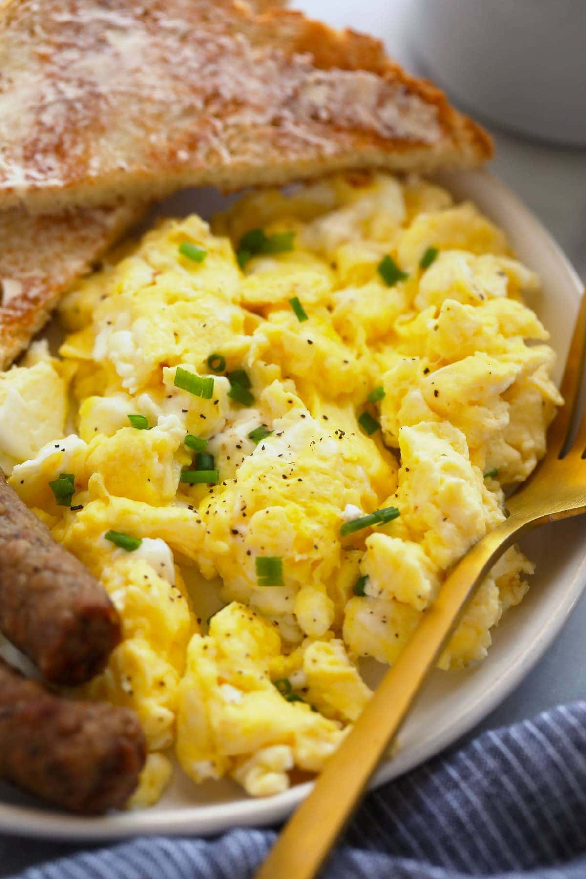 perfect scrambled eggs on a plate with toast and sausage links, ready to be served