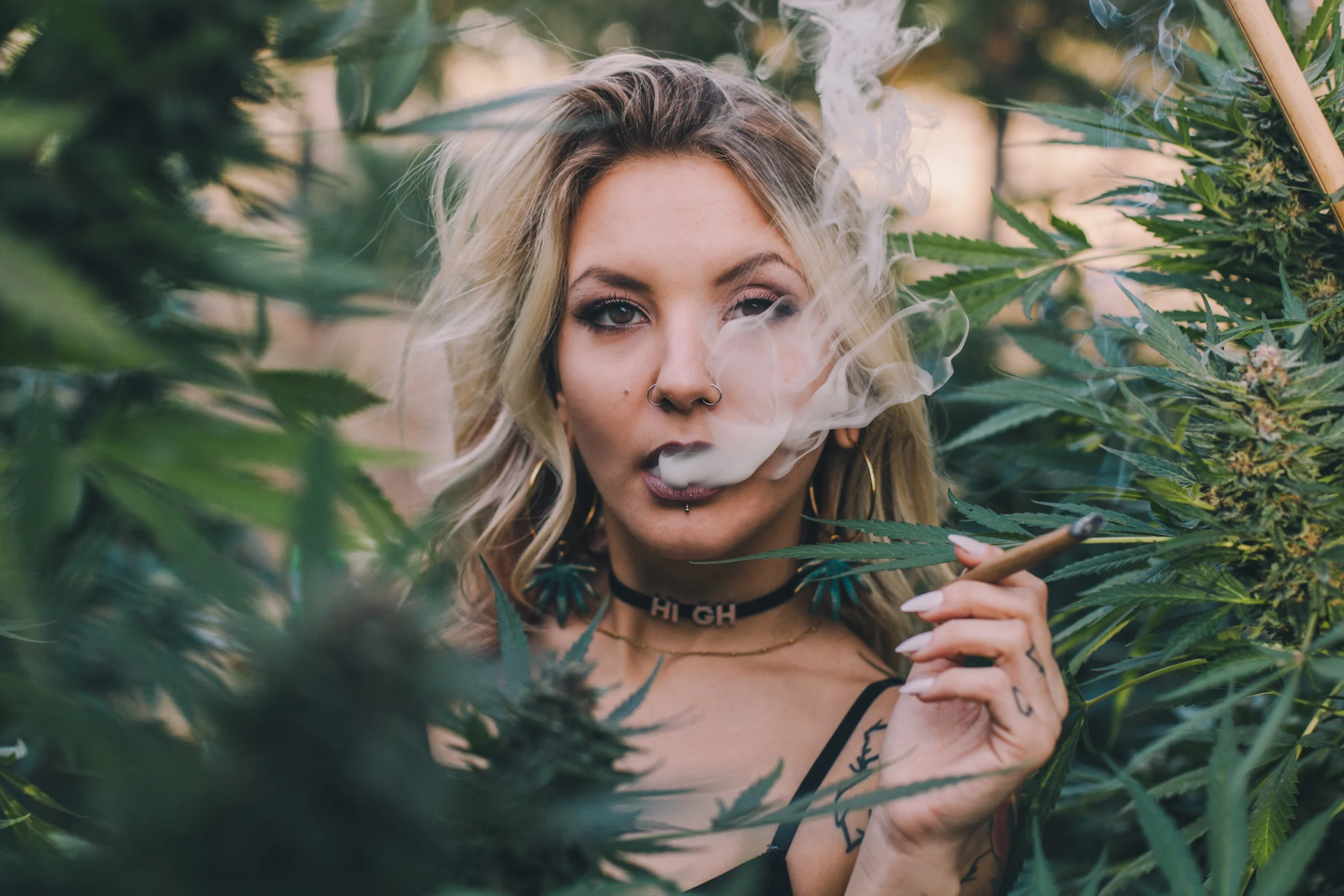 weed strains - beautiful woman smoking weed amongst cannabis plants