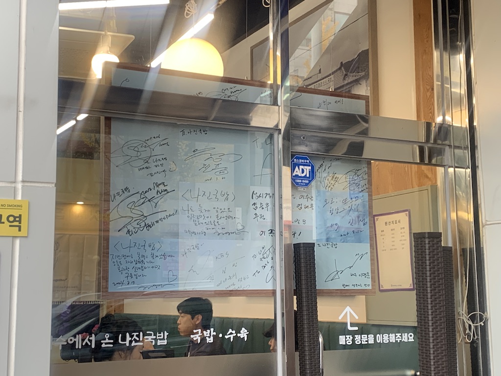 a glass wall with signs and a person in a hat