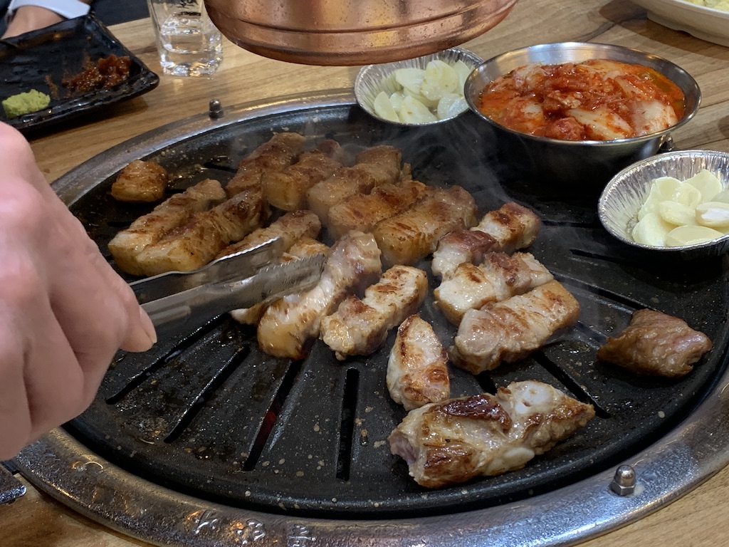 a person holding a knife over a grill with food on it