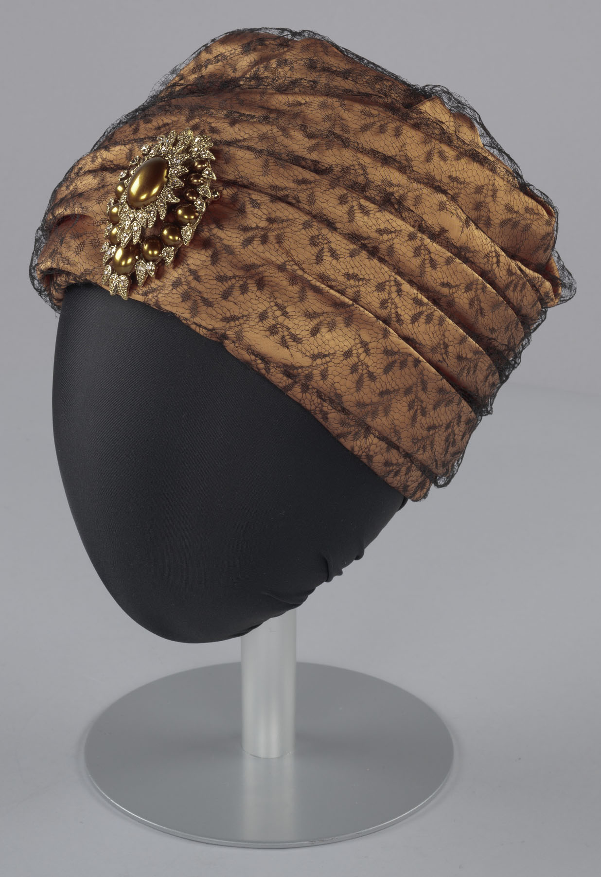 A head wrap made from silk satin, net, buckram, metal, and glass, designed by Mae Reeves (1912–2016). 