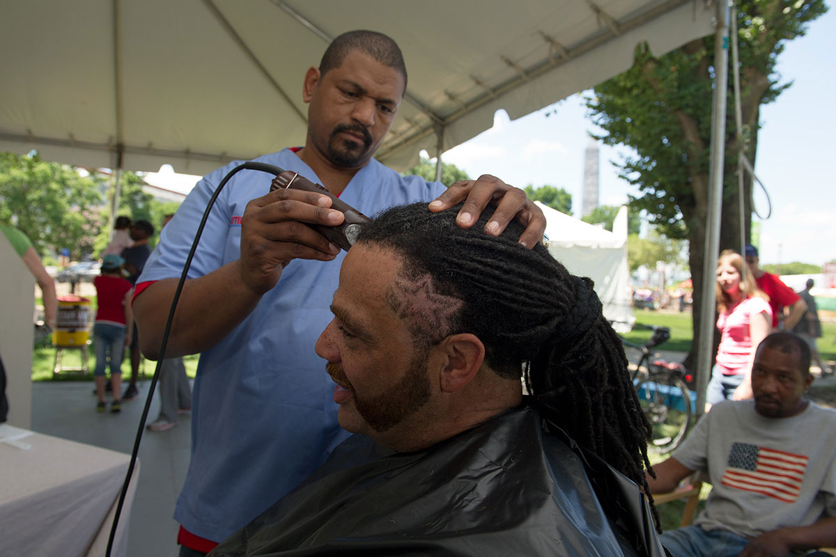 Dennis “Denny Moe” Mitchell of Harlem, New York, gives a haircut on the National Mall.