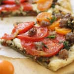 Goat cheese tomato sausage tart on a cutting board.