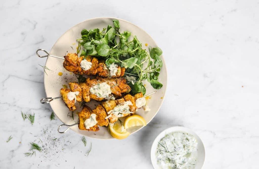 A plate of shawarma kebabs with greens and lemon slices.