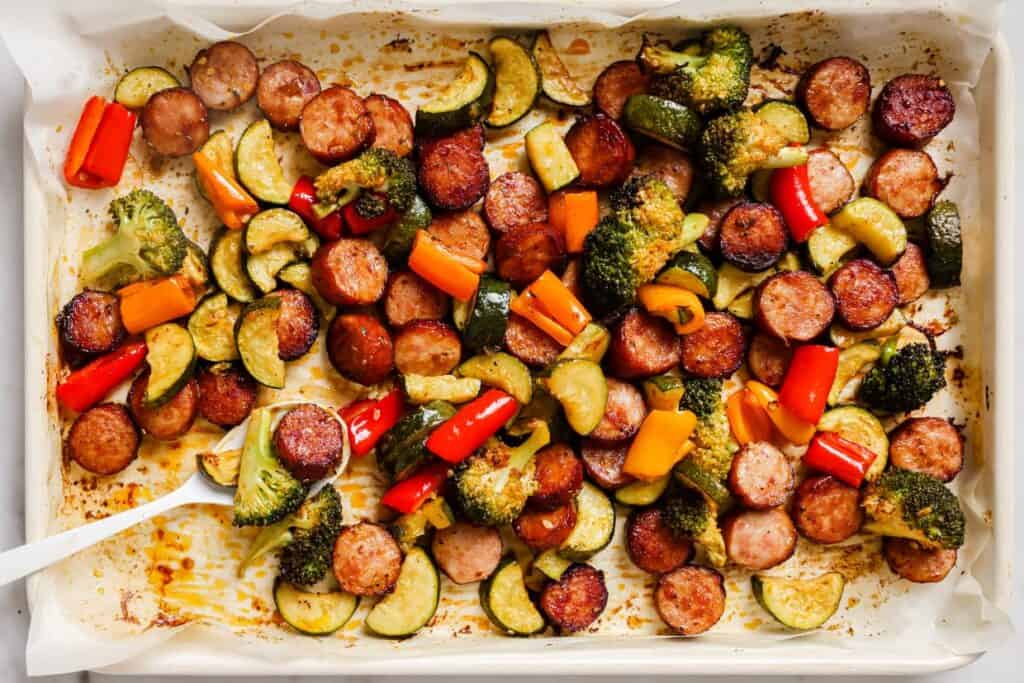 A baking sheet filled with vegetables and sausages.