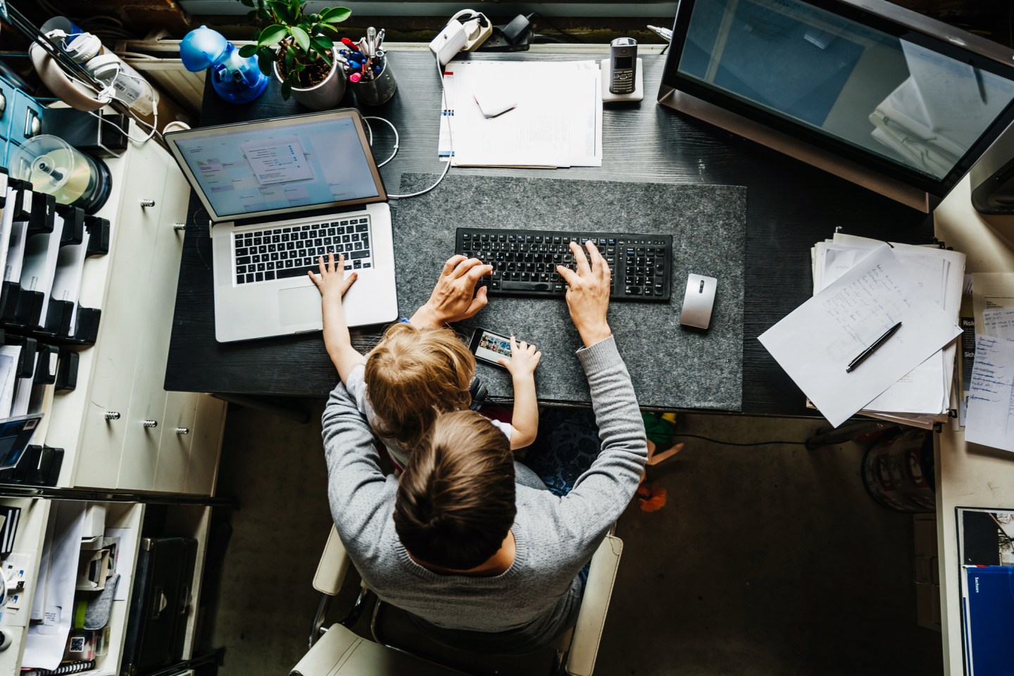 Aerial View Of Mother Working In Office At Home With Daughter