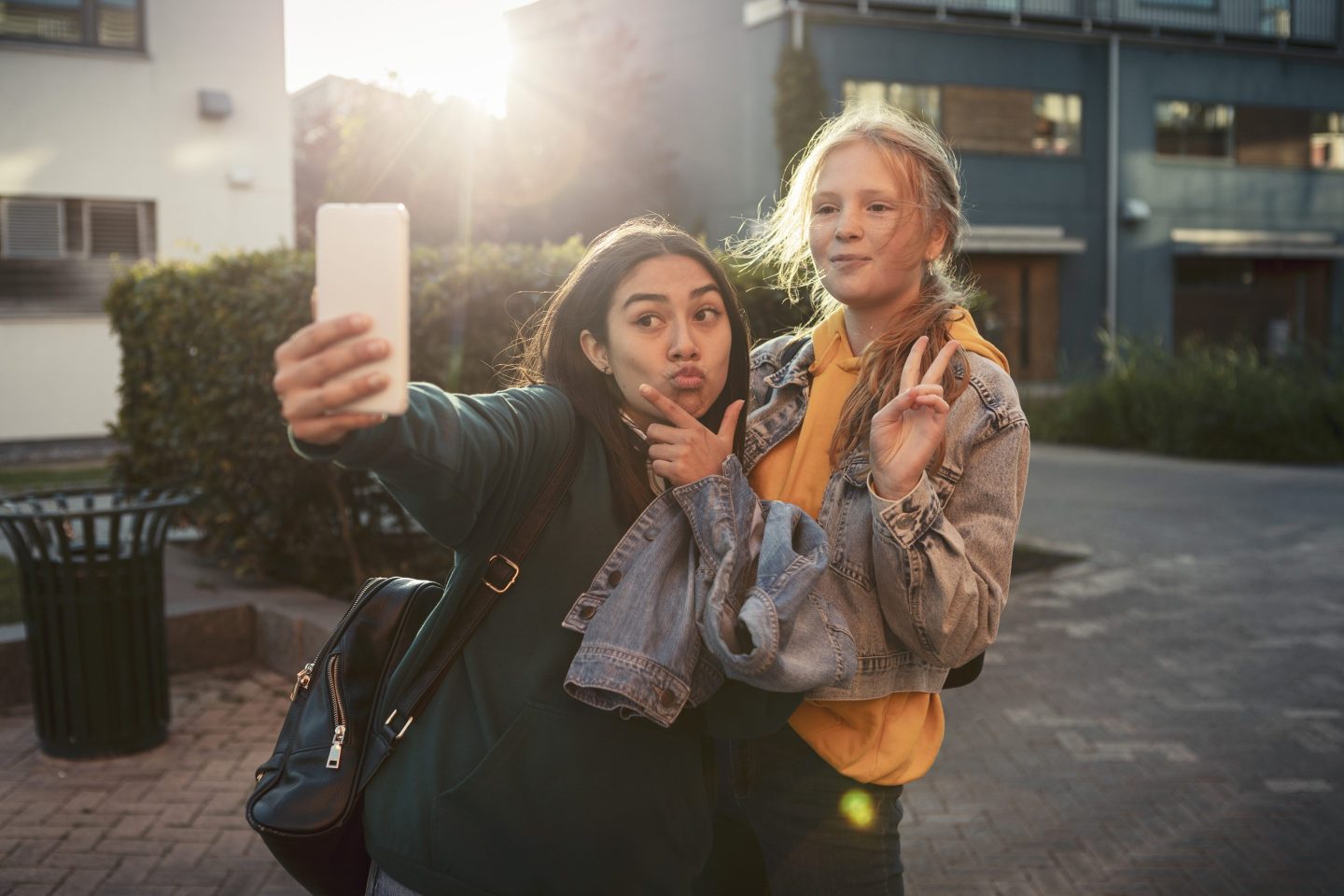 Young teens take selfies under bright lights.