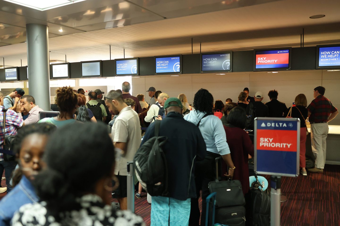 Airline customers wait in line for service at a Delta desk after mass cancellations and delays