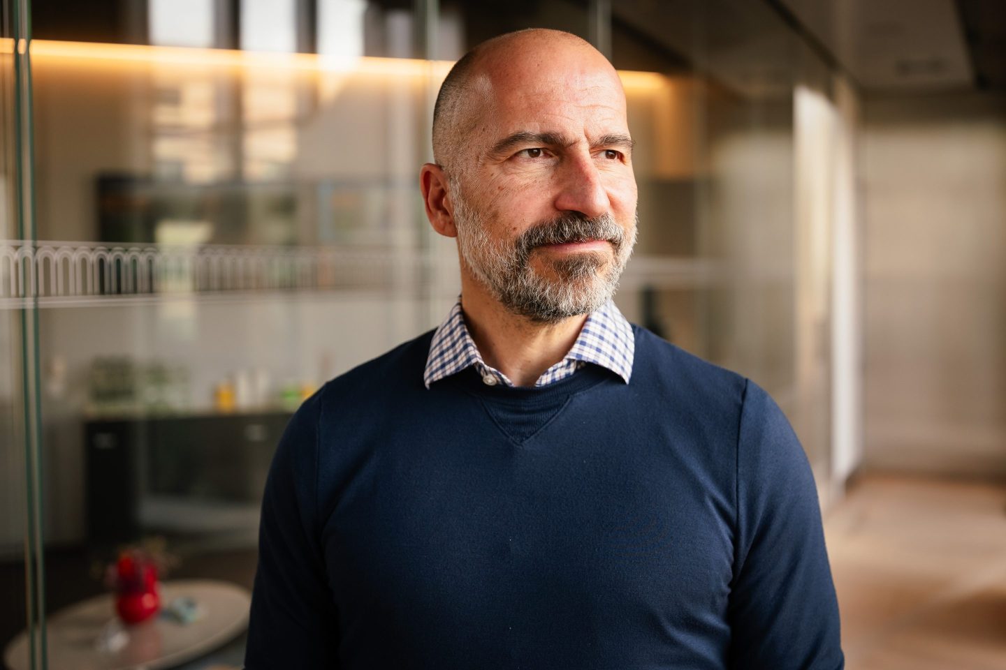 Dara Khosrowshahi, chief executive officer of Uber Technologies Inc. in a deep navy blue sweater layered over a collared shirt. He is looking away from the camera, confidently.