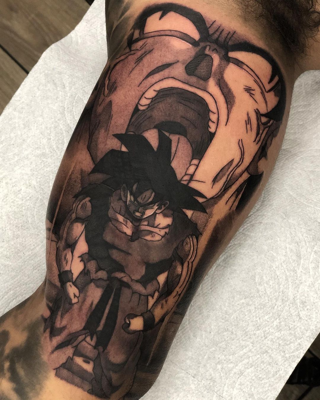 "Detailed tattoo of Son Goku in Super Saiyan form on forearm, showcasing intense expression with a shattered background, ideal for Dragon Ball Z enthusiasts."