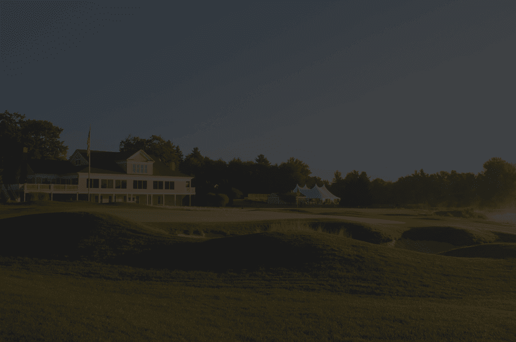 Golf clubhouse at golden hour with a putting green in the foreground