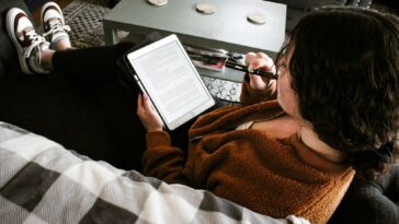 a person sitting on a couch with a tablet and a laptop