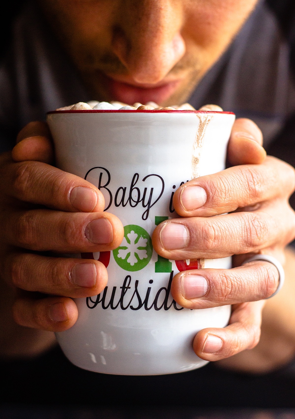 a man's hands wrapped around a cup of hot cocoa