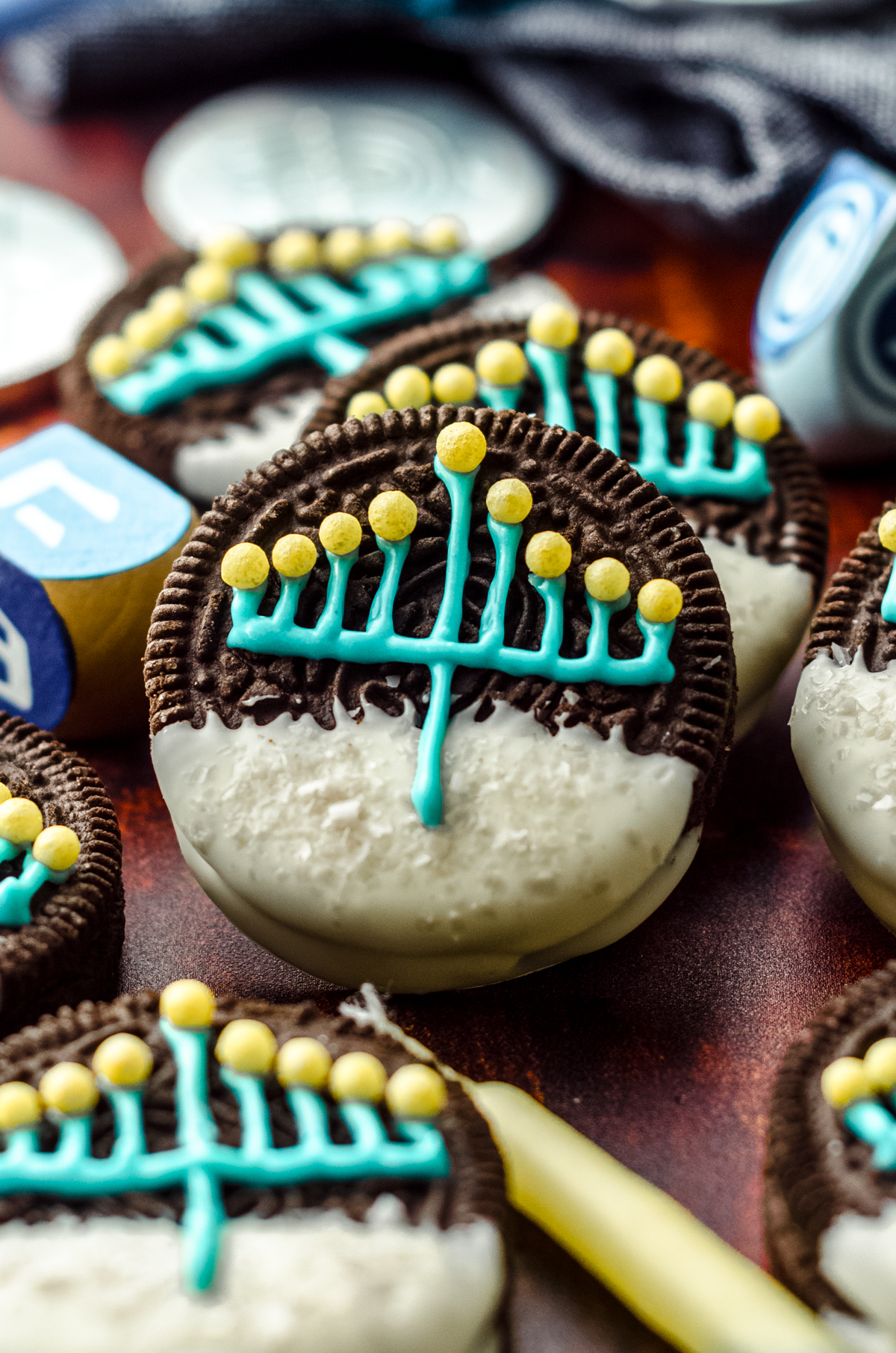 Hanukkah Oreos on a surface surrounded by candles and dreidels.