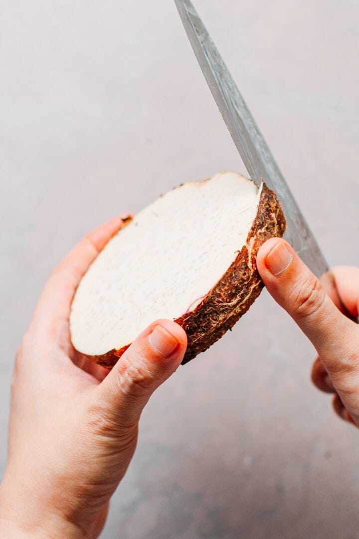 Peeling a slice of raw taro.