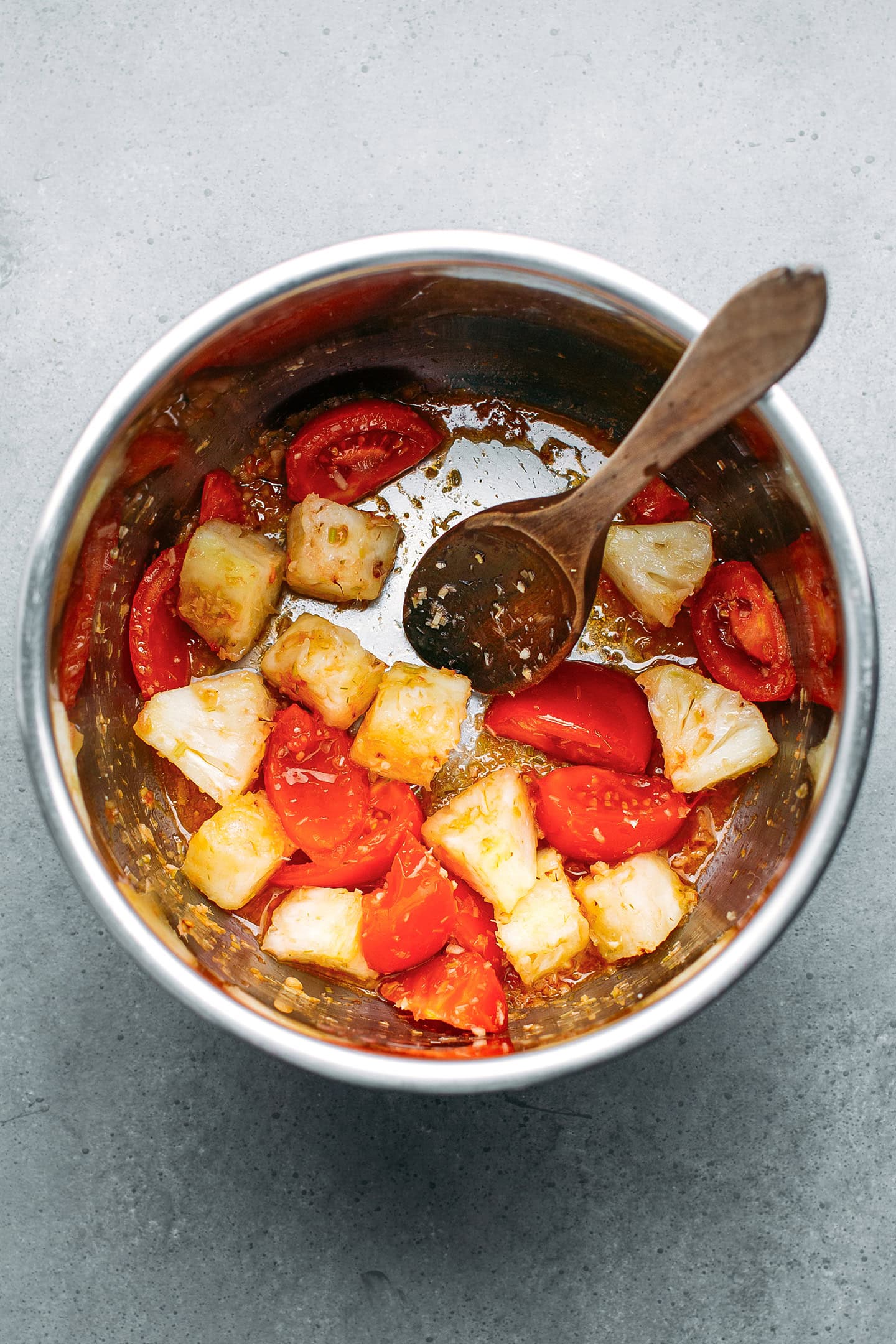 Chopped pineapple and tomatoes in a pot.