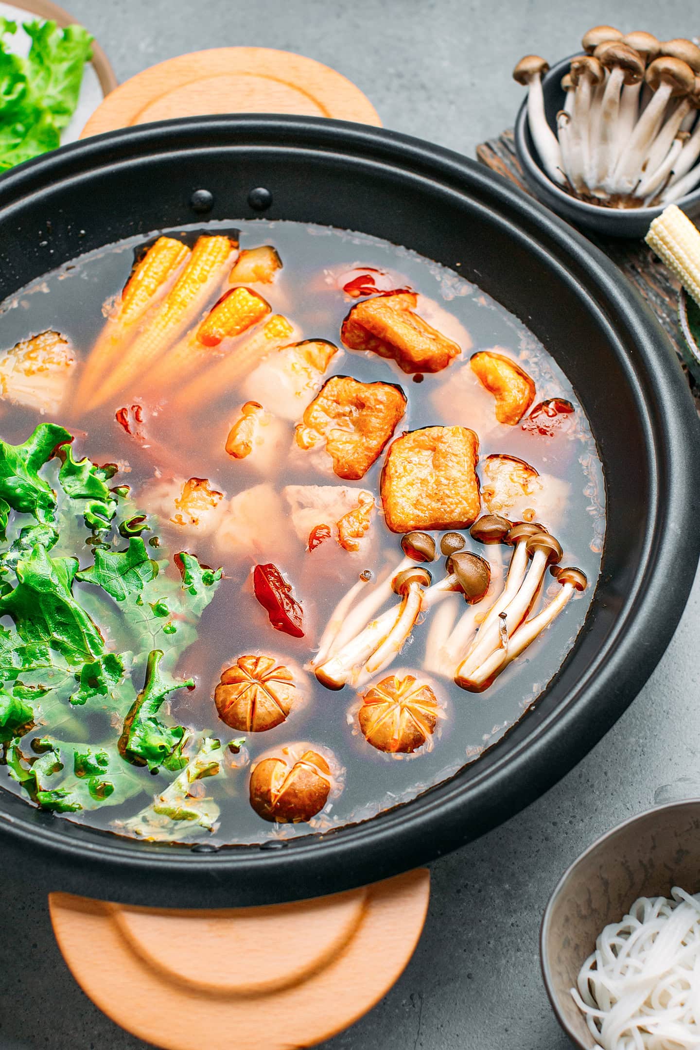 Pot filled with sweet and sour broth, tofu puffs, mushrooms, and pineapple.